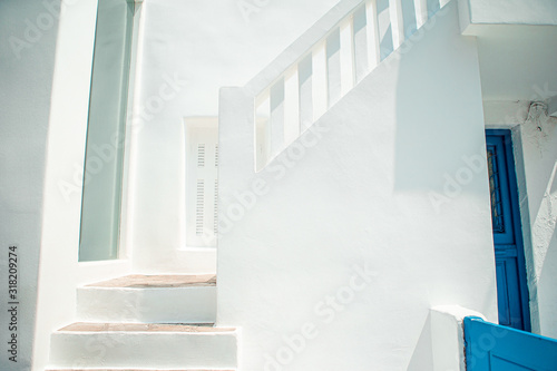 Fototapeta Naklejka Na Ścianę i Meble -  The narrow streets of the island with blue balconies, stairs and flowers in Greece.
