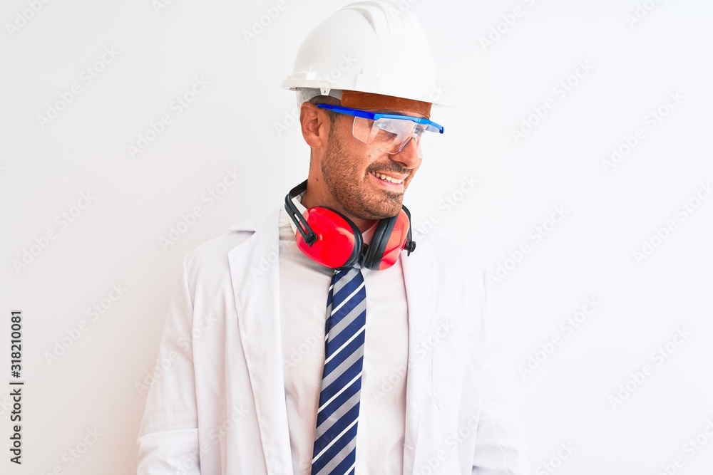 Young chemist man wearing security helmet and headphones over isolated background looking away to side with smile on face, natural expression. Laughing confident. Young chemist man wearing security helmet and headphones over isolated background looking away to side with smile on face, natural expression. Laughing confident.