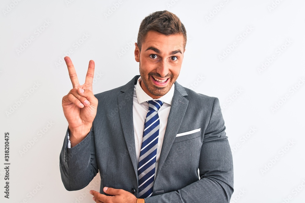 Young handsome business man wearing suit and tie over isolated background smiling with happy face winking at the camera doing victory sign with fingers. Number two. Young handsome business man wearing suit and tie over isolated background smiling with happy face winking at the camera doing victory sign with fingers. Number two.