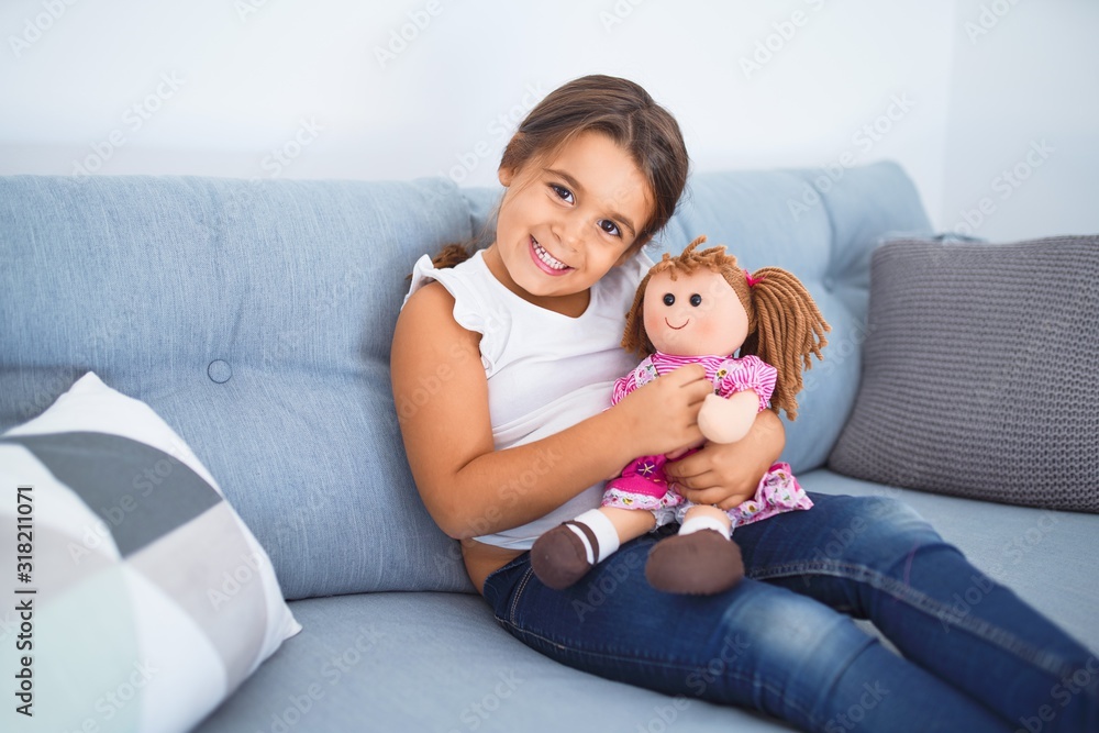 Adorable toddler smiling happy. Sitting on the sofa hugging doll at home Adorable toddler smiling happy. Sitting on the sofa hugging doll at home