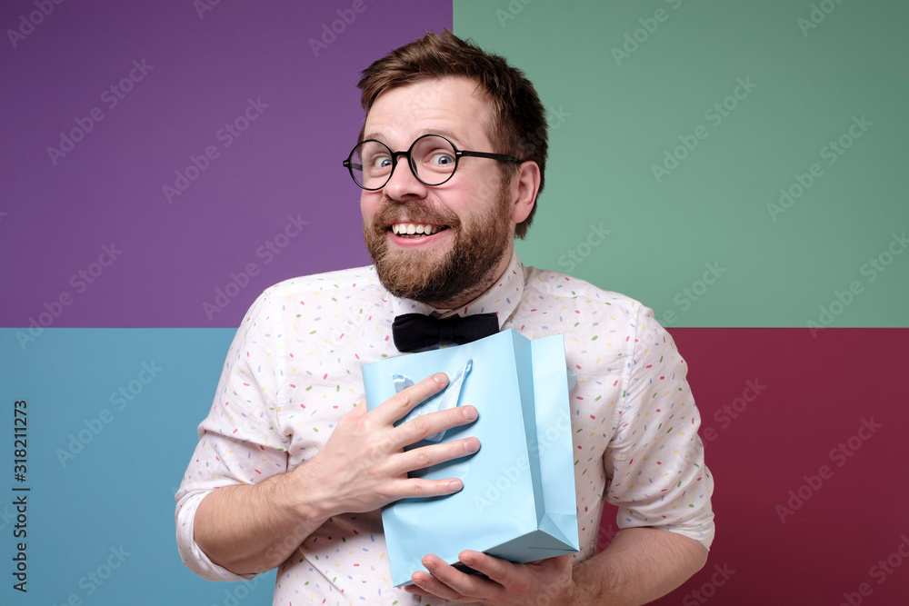 Man received a pleasant surprise, he is happy, joyfully presses a package with a gift to chest, smiles and looks at the camera. Man received a pleasant surprise, he is happy, joyfully presses a package with a gift to chest, smiles and looks at the camera.