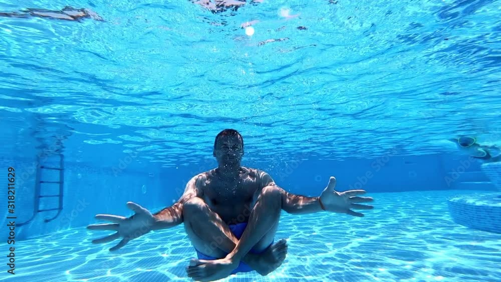 Man sitting underwater in yoga pose. Underwater view inside the
