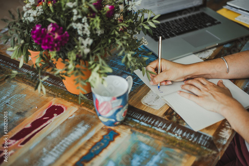 Mujer escribiendo en bonita oficina moderna y floral