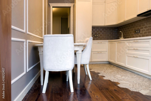 Facade of a white, wooden kitchen with a table and chairs. Scandinavian style kitchen design
