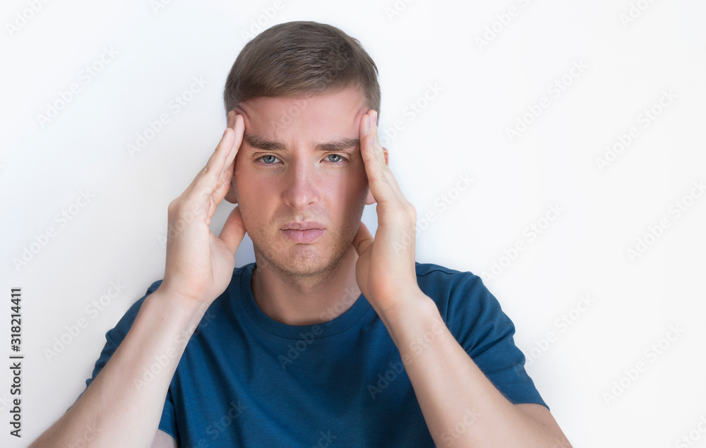 Person suffering from feeling pain because severe headache, migraine. Handsome nice guy, young annoyed upset man holding his head with hands, temples with fingers, looking at camera. Face expression Person suffering from feeling pain because severe headache, migraine. Handsome nice guy, young annoyed upset man holding his head with hands, temples with fingers, looking at camera. Face expression