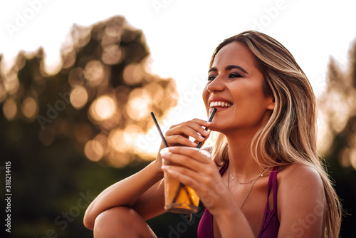 Bilde på lerret Summer portrait of a positive girl sipping drink on a straw outdoors