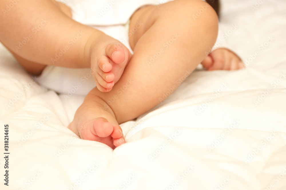 Legs of infant on the white blanket, bedroom, blurred background