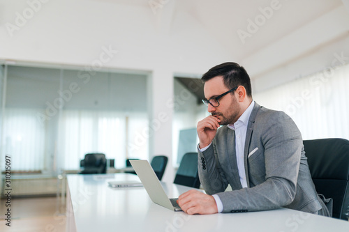 Portrait of a pensive businessman looking at laptop, copy space.