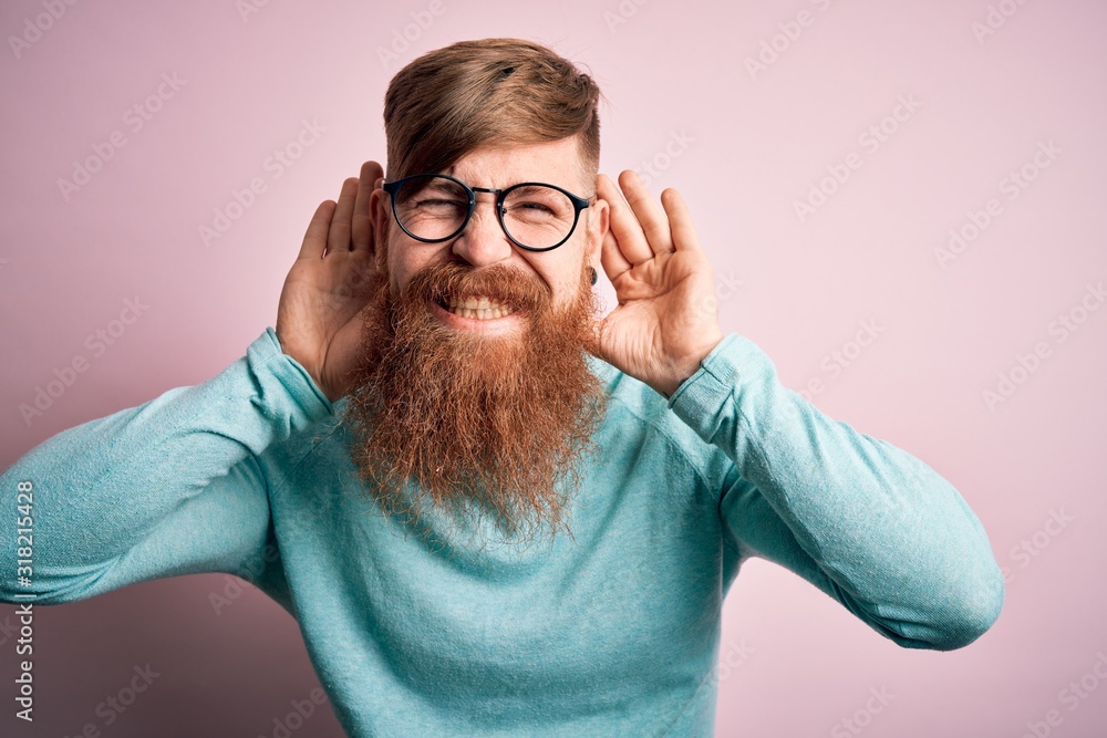 Handsome Irish redhead man with beard wearing glasses over pink isolated background Trying to hear both hands on ear gesture, curious for gossip. Hearing problem, deaf Handsome Irish redhead man with beard wearing glasses over pink isolated background Trying to hear both hands on ear gesture, curious for gossip. Hearing problem, deaf