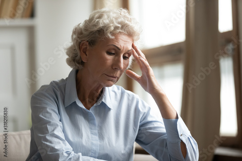 Stressed mature elderly grandmother feeling unwell, sitting alone at home.