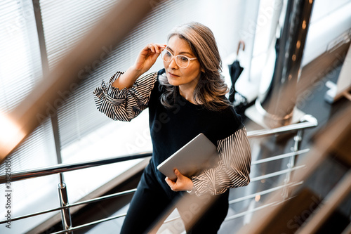 Bilde på lerret Woman touching the glasses while walking upstairs stock photo