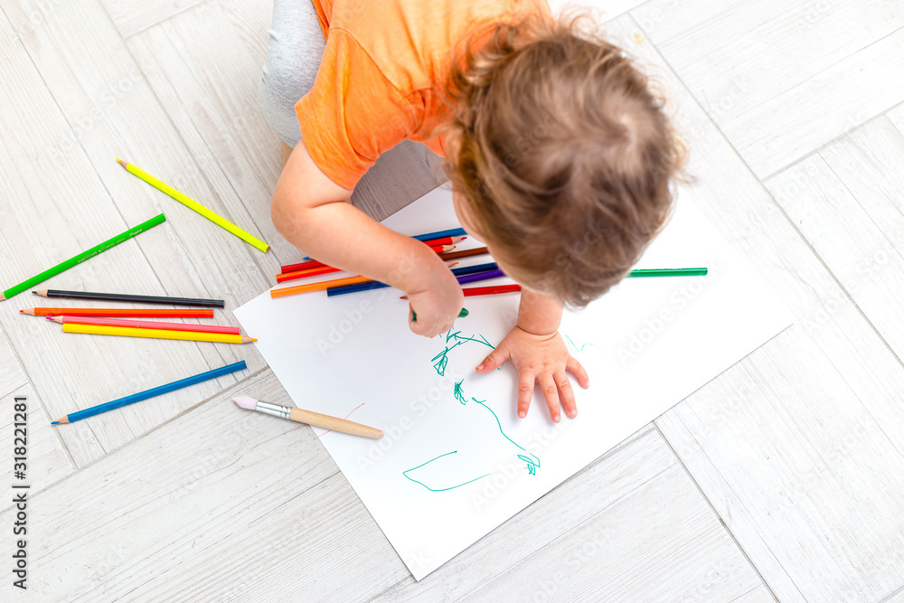 Curly girl draws with pencils on a white sheet of paper at home. Flat lay Curly girl draws with pencils on a white sheet of paper at home. Flat lay