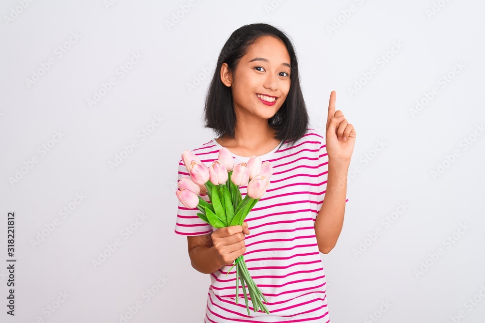 Young chinese woman holding bouquet of roses standing over isolated white background surprised with an idea or question pointing finger with happy face, number one Young chinese woman holding bouquet of roses standing over isolated white background surprised with an idea or question pointing finger with happy face, number one