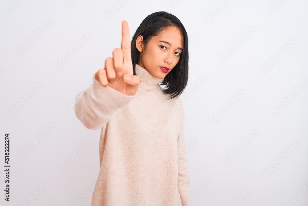 Young chinese woman wearing turtleneck sweater standing over isolated white background Pointing with finger up and angry expression, showing no gesture Young chinese woman wearing turtleneck sweater standing over isolated white background Pointing with finger up and angry expression, showing no gesture