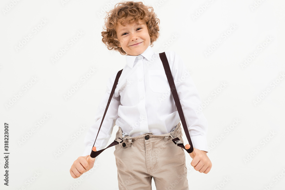 Charming boy with curly hair in white shirt with black suspenders stands isolated on white background Charming boy with curly hair in white shirt with black suspenders stands isolated on white background