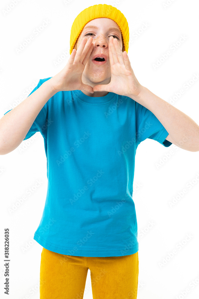 Cool teenager girl with red hair, blue t-shirt and yellow hat screams isolated on white background Cool teenager girl with red hair, blue t-shirt and yellow hat screams isolated on white background