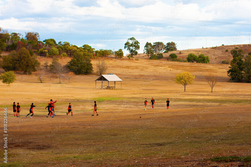 Obraz premium A group of children in the distance playing football (soccer) in a clearing (a meadow) among the hills