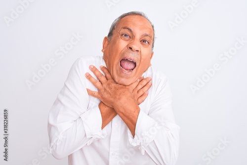 Senior grey-haired man wearing elegant shirt standing over isolated white background shouting and suffocate because painful strangle. Health problem. Asphyxiate and suicide concept.