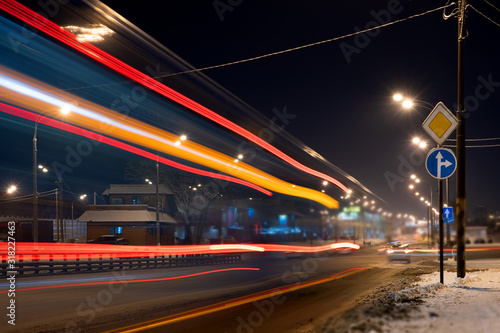 Night winter city in the snow. Cars passing by, smeared beautiful light from cars. Long exposure, blurry light from cars.