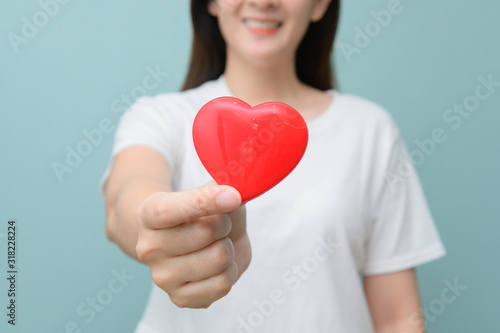 Woman holding heart figure. Romantic valentines day scene with girl on pink background. Woman holding red heart against color background.
