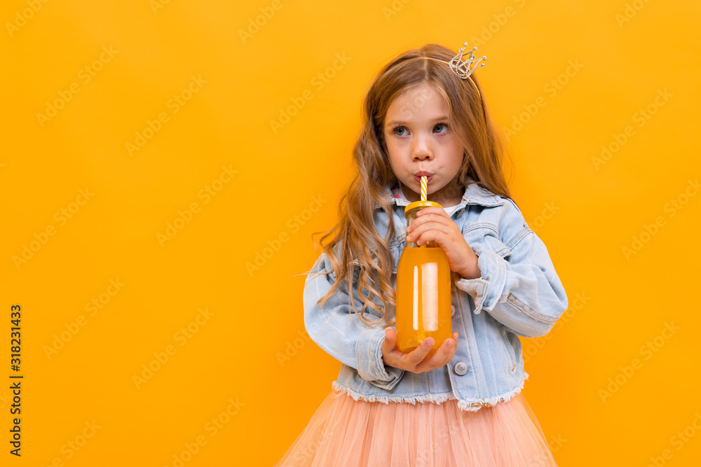 attractive caucasian young girl with a glass of orange juice posing on a yellow studio background with copy space attractive caucasian young girl with a glass of orange juice posing on a yellow studio background with copy space