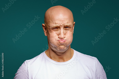 portrait of a bald man puffed out his cheeks on a blue background photo