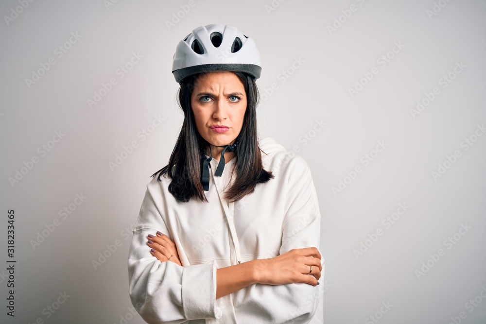 Young cyclist woman with blue eyes wearing bike helmet over isolated white background skeptic and nervous, disapproving expression on face with crossed arms. Negative person. Young cyclist woman with blue eyes wearing bike helmet over isolated white background skeptic and nervous, disapproving expression on face with crossed arms. Negative person.