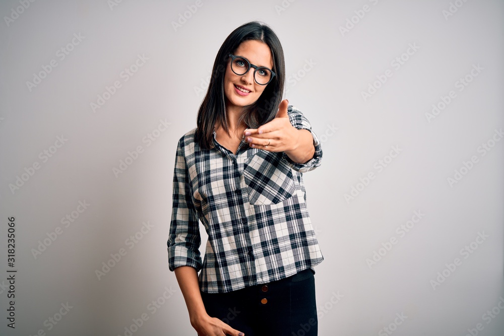 Young brunette woman with blue eyes wearing casual shirt and glasses over white background smiling cheerful offering palm hand giving assistance and acceptance. Young brunette woman with blue eyes wearing casual shirt and glasses over white background smiling cheerful offering palm hand giving assistance and acceptance.