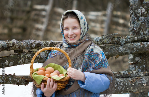 Tableau sur toile A young girl in a Russian scarf with a basket of chicken eggs