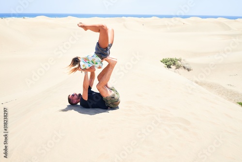 Young beautiful couple trainning acroyoga at the beach