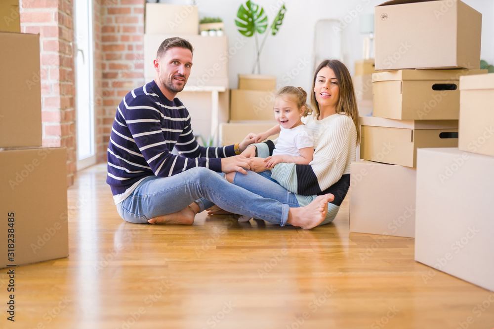 Beautiful family sitting on the floor playing with his kid at new home around cardboard boxes Beautiful family sitting on the floor playing with his kid at new home around cardboard boxes