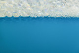 soap bubbles in water at the top of the macro picture. There is empty space for text on a blue background.