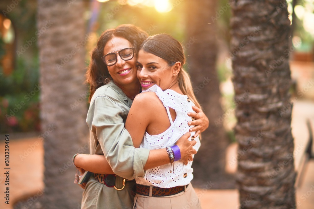 Beautiful mother and daughter smiling happy and confident. Standing with smile on face hugging at town park Beautiful mother and daughter smiling happy and confident. Standing with smile on face hugging at town park