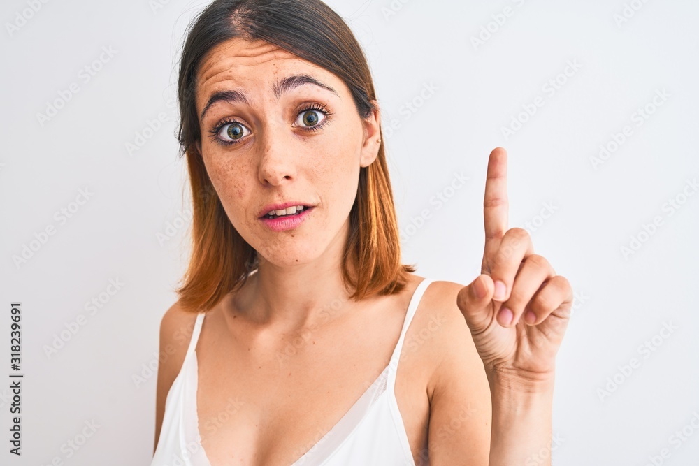 Beautiful redhead woman wearing casual white t-shirt over isolated background surprised with an idea or question pointing finger with happy face, number one Beautiful redhead woman wearing casual white t-shirt over isolated background surprised with an idea or question pointing finger with happy face, number one