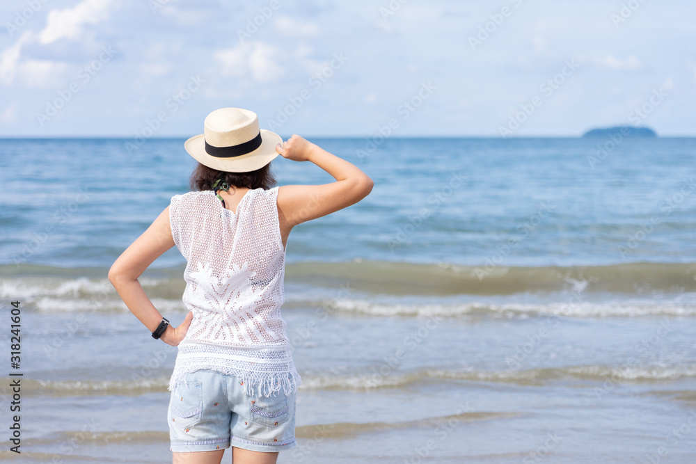 Outdoor summer portrait of Young Asian woman wearing stylish hat and clothes standing on the beach, enjoying looking view of sea with blue sky on summer vacation. Outdoor summer portrait of Young Asian woman wearing stylish hat and clothes standing on the beach, enjoying looking view of sea with blue sky on summer vacation.