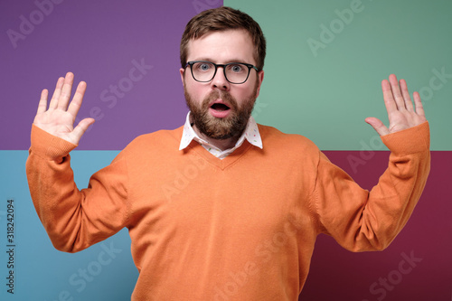 Spineless  bearded Caucasian does not want conflict  he raised hands up  opened his mouth in fear and looks into the camera.