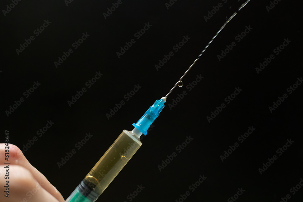 Syringe with injection drops on a black background with a copy of the space Syringe with injection drops on a black background with a copy of the space