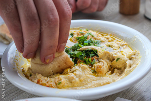 A man picks up a pita hummus in Israel photo