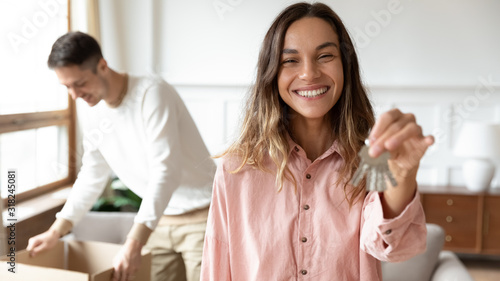 Smiling young wife show keys moving together with spouse photo
