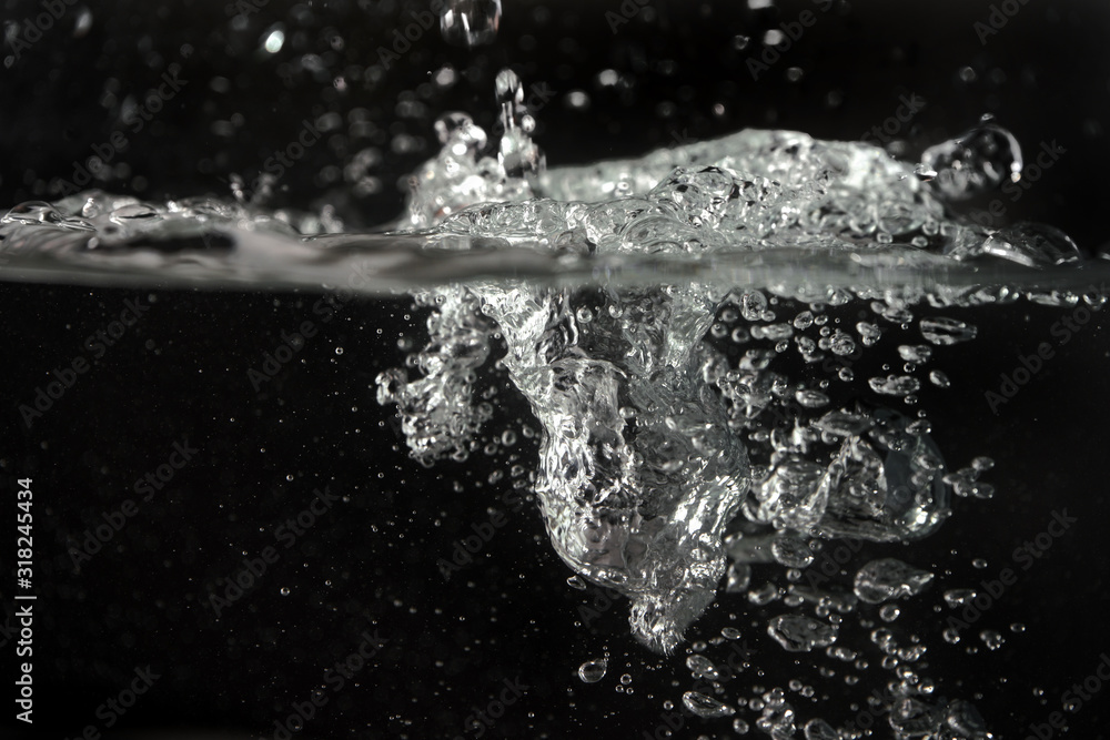 Water splashing as it's poured into aquarium tank, black background Water splashing as it's poured into aquarium tank, black background