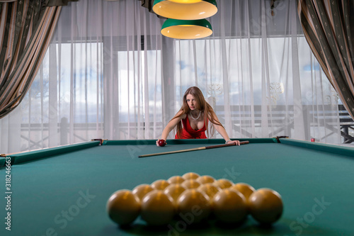 blonde girl with gorgeous breasts dressed in an elegant evening dress and came to the billiard club to conquer everyone with her beauty and surprise with how masterfully she plays photo