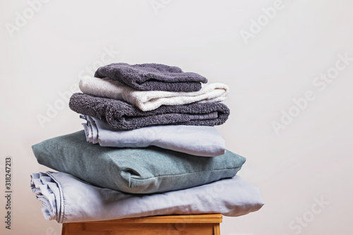 Pile of clean folded home textile items near the white wall. photo