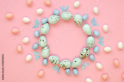 Easter circle shape frame made of decorated quail eggs on a pink table. Top view with space for lettering