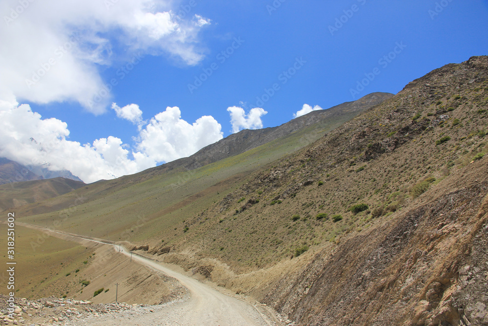 Dirt road in the mountains of Nepal on a background of blue sky and beautiful clouds