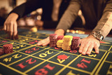 Close up of people hands laying chips on roulette table in casino.