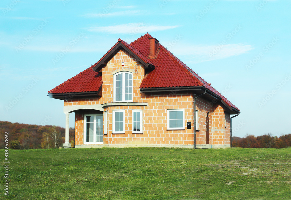 Jaslo, Poland - 7 8 2018: Modern design of a small single-family house located in a rural area. Designing buildings and landscape. New home for people. Red metal roof. Energy saving and greenhouse eff