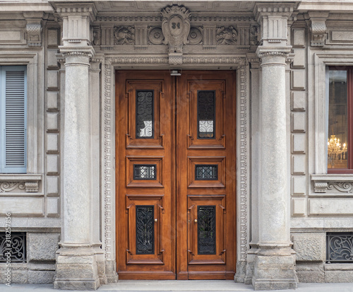 luxurious entrance door inserted between two columns, of a palace at number 31 on a street in Milan