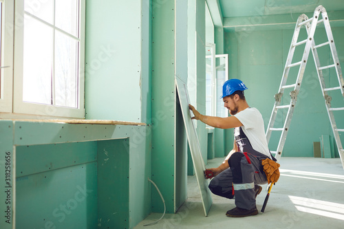 Quadro su tela Worker builder installs plasterboard drywall at a construction