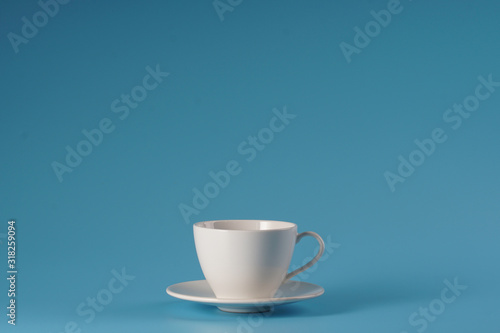 White ceramic cup over isolated blue bcakground