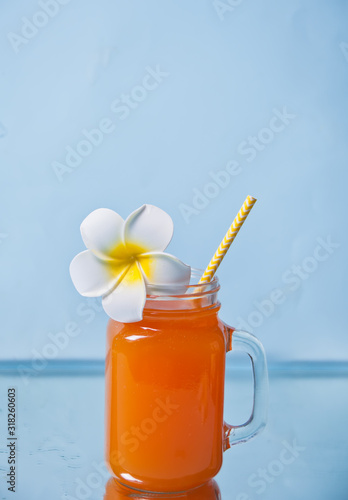 Glass of tropical exotic multifruit juice cocktail drink with Plumeria frangipani flower for decoration.